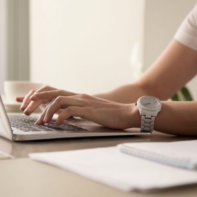 Close up image of womans hands typing on laptop at workplace. Businesswoman with white wristwatch on hand working on computer in office. Female office worker, programmer, entrepreneur searching online